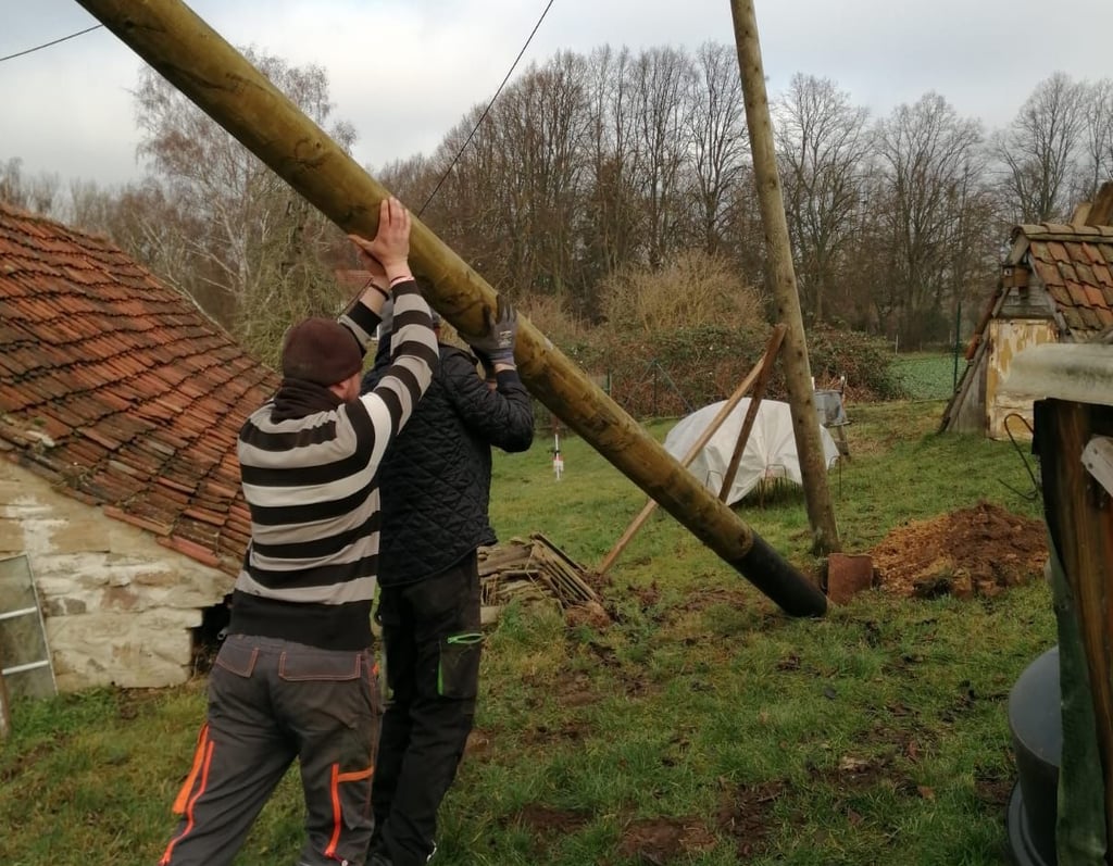 Zwei Monteure richten den neuen Mast auf. Erst wenn die Leitung dort wieder angeklemmt ist, kann der alte entfernt werden.