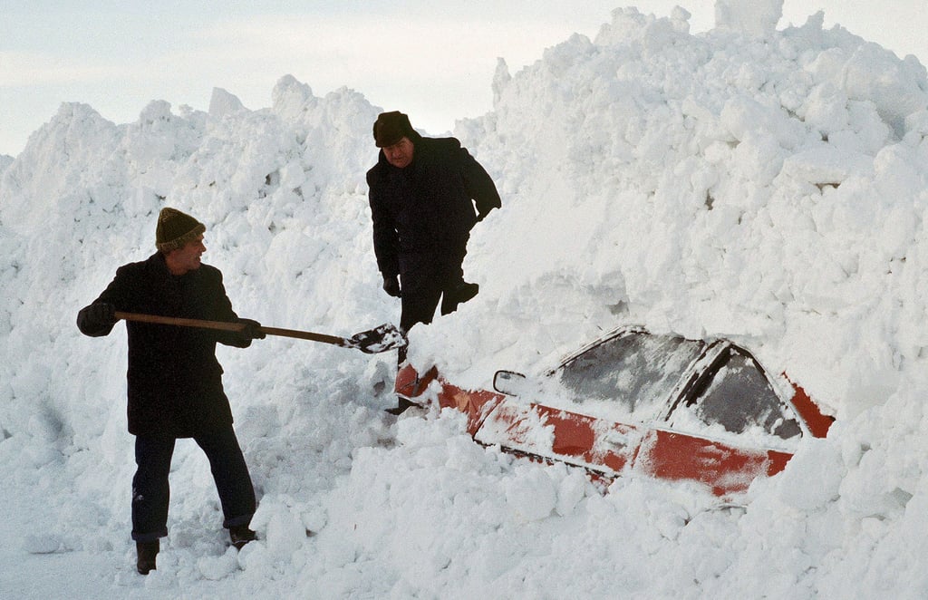 Zwei Männer graben im Winter 1978/79 ein Auto aus den Schneemassen. Städte und Dörfer in Teilen Deutschlands – egal ob Ost oder West – waren von der Außenwelt abgeschnitten, der Zugverkehr kam zum Erliegen und auf Autobahnen türmten sich Schneemassen auf.