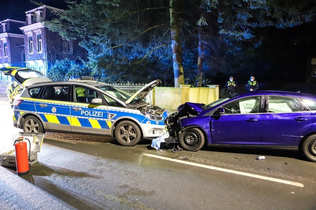 Ein Streifenwagen der Polizei und ein weiteres Auto stehen nach einem Unfall auf einer Straße.