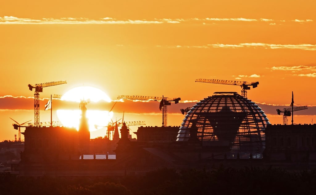 Baukräne und die Kuppel des Reichstagsgebäudes in Berlin. Die deutsche Wirtschaft kommt wieder in Schwung.