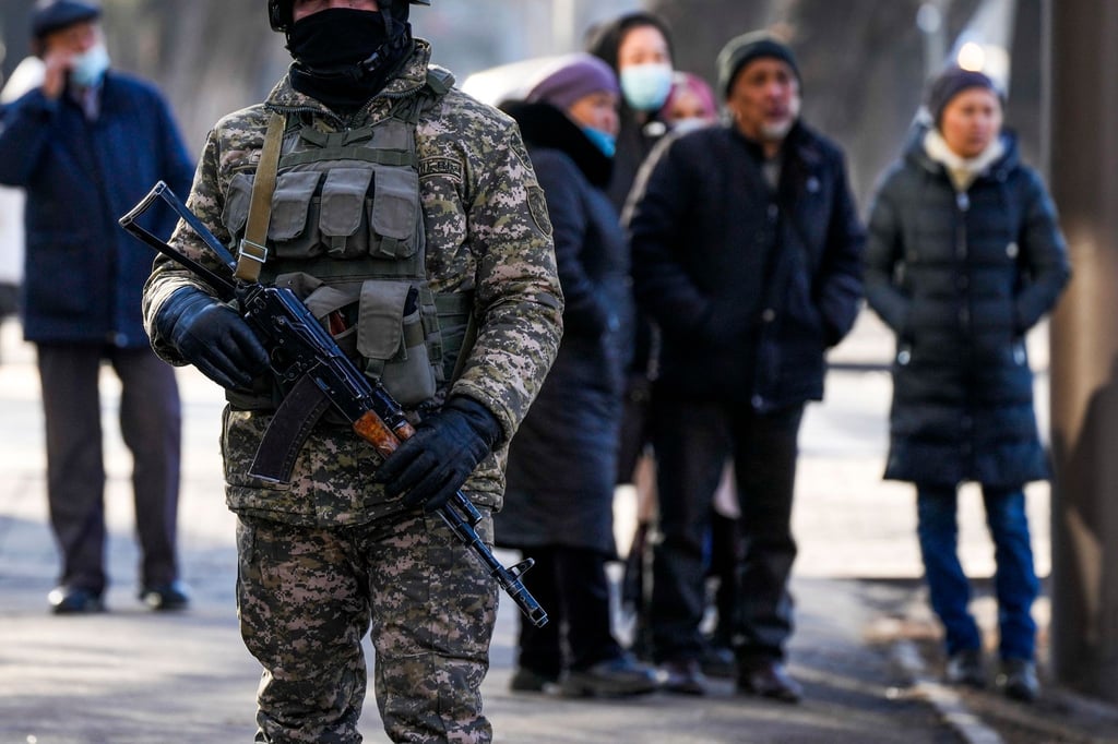 Ein kasachischer Soldat patrouilliert in Almaty nahe einer Polizeistation. Hinter ihm versammeln sich Angehörige von Personen, die nach den Protesten gegen die Regierung verhaftet wurden.