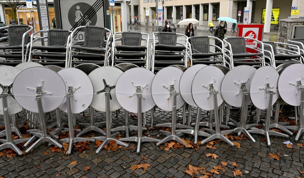 Zusammengestellte Stühle und Tische stehen vor einem Café in München.