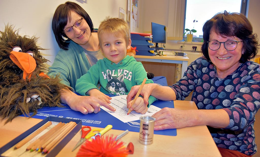 Nadine Schwermer (l.) und Carola Lange, Beraterinnen der Paritätischen Sozialwerke GmbH Kinder- und Jugendhilfe, zeigen dem fünfjährigen Anton im „Ein Haus für Alle“ (EHFA), wie er als Linkshänder zum Beispiel die Stifte zum Malen und Schreiben richtig hält.