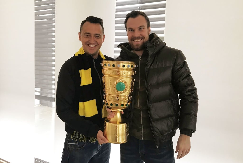 Gastronom Christopher Reinecke (l) und sein Geschäftspartner Kevin Großkreutz mit dem Duplikat des DFB-Pokals.