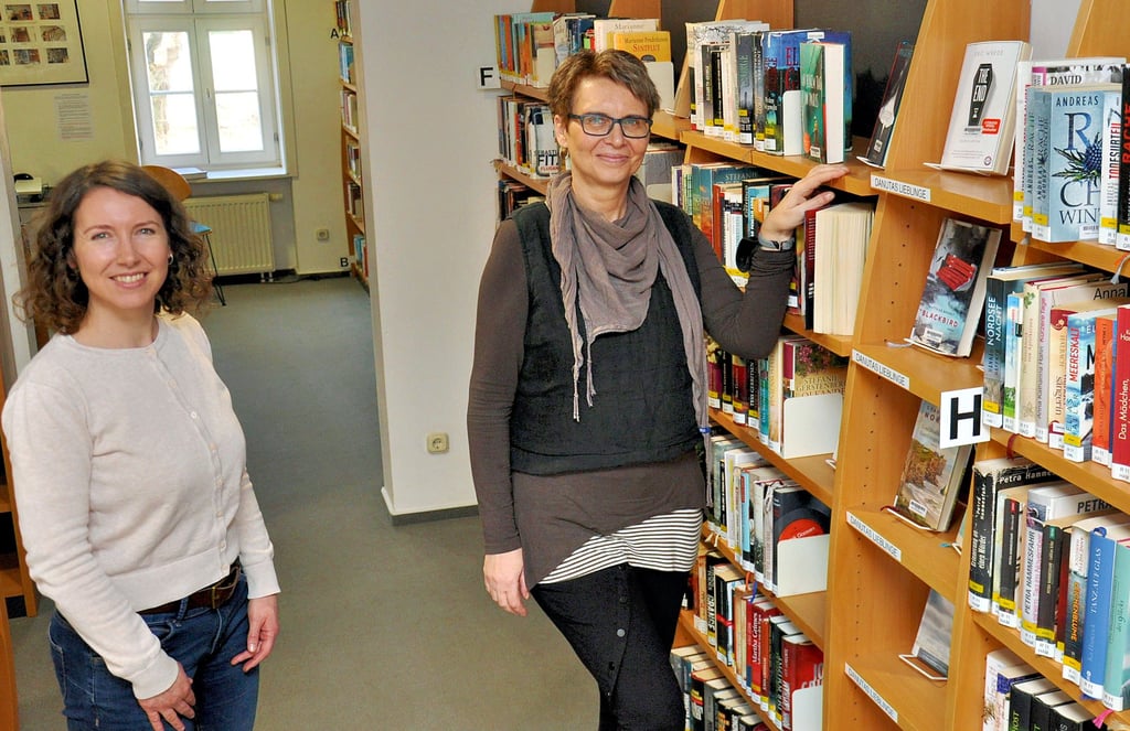Anette Rieger und Danuta Ahrends vor „Danutas Lieblingen“. In diesem Regal hat die für Belletristik zuständige Bibliotheksmitarbeiterin Danuta Ahrends seit 2021 eigene Favoriten platziert.