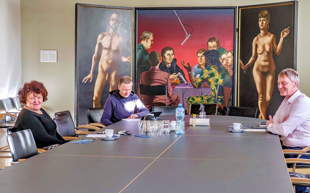 Bereiten sich auf eine besondere Sprechstunde vor: Marianne Schröter, Paul Martin (Mitte) und Dirk Rademacher, hier in einem Seminarraum der Stiftung Leucorea in Wittenberg. Im Hintergrund zu sehen ist das Gemälde „Tischgespräch mit Luther“ des Hallenser Künstlers Uwe Pfeifer.