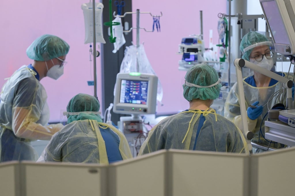 Pflegerinnen und Pfleger sowie eine Ärztin kümmern sich auf der Intensivstation um einen Patienten.