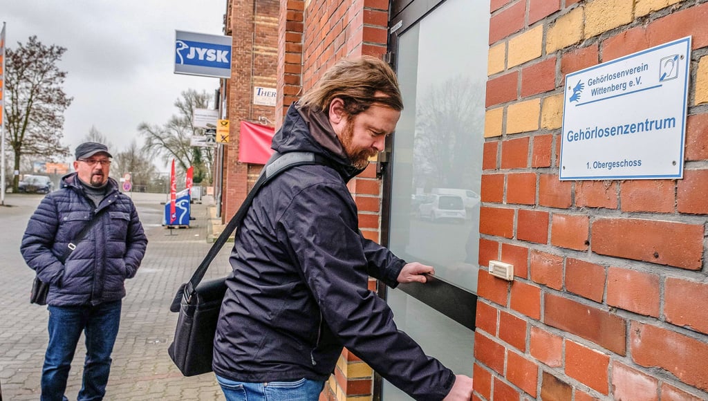 Christoph Melle öffnet die Tür des Gehörlosenzentrum in der Wittenberger Straße. Im Hintergrund wartet Uwe Kapper.