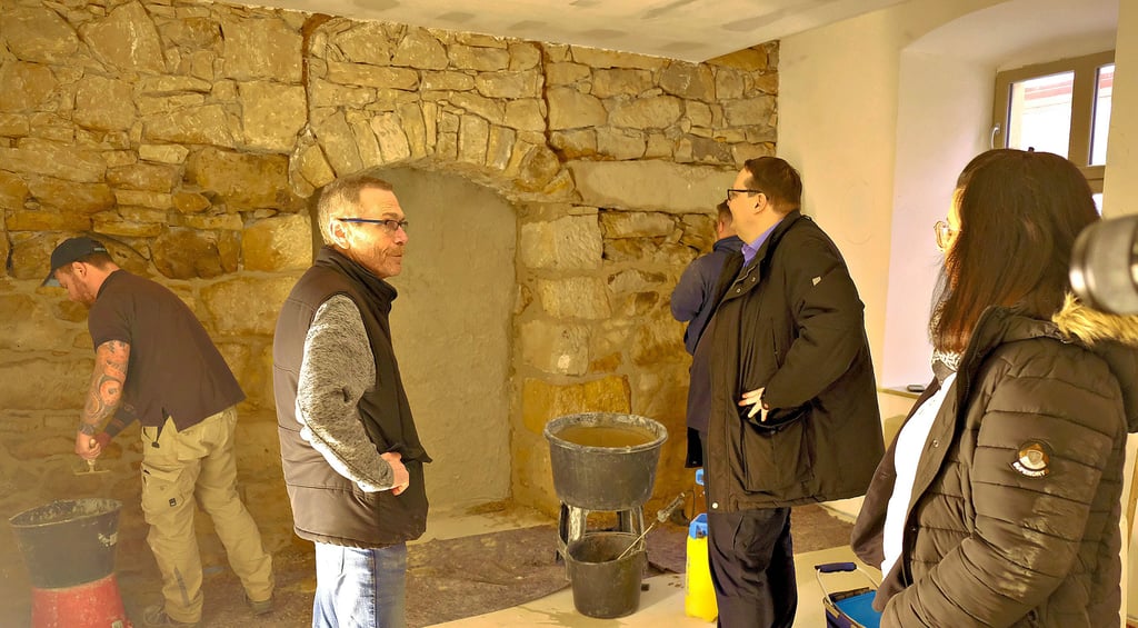 Das sogenannte Forsthaus in Blankenburg wird aktuell saniert. Projektleiter Gerhard Bleile führte Bürgermeister Heiko Breithaupt und Bauamtsleiterin Madeleine Bürger (von links) über die Baustelle. Hier verfugen Mitarbeiter der Bauhütte Quedlinburg eine historische Sandsteinwand in einer der künftigen Wohnungen.