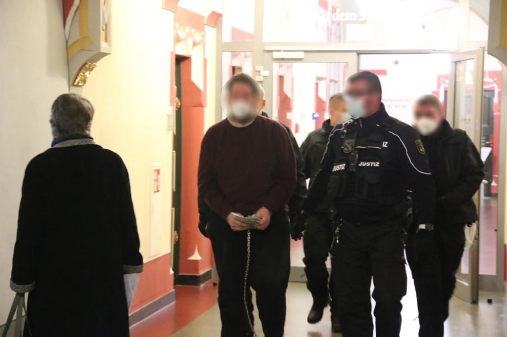 Der Angeklagte beim Prozesauftakt auf dem Weg ins Gericht. Er wurde gleich von mehreren Justizbeamten in den Saal 141 gebracht.