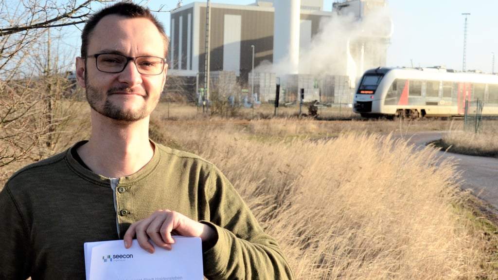 Lennart Victor ist der Klimaschutzmanager für Haldensleben. Zu seinen Aufgaben zählt, das Klimaschutzkonzept der Stadt Haldensleben umzusetzen. Ein Projekt darin ist die Nutzung industrieller Abwärme, die beispielsweise bei Unternehmen wie Euroglas (im Hintergrund) entsteht, für das Nahwärmenetz.