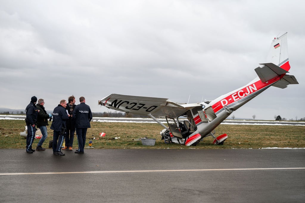 Die ermittelnden Polizeibeamten stehen neben dem verunglücktem Kleinflugzeug Cessna auf dem Flugplatz in Coburg.