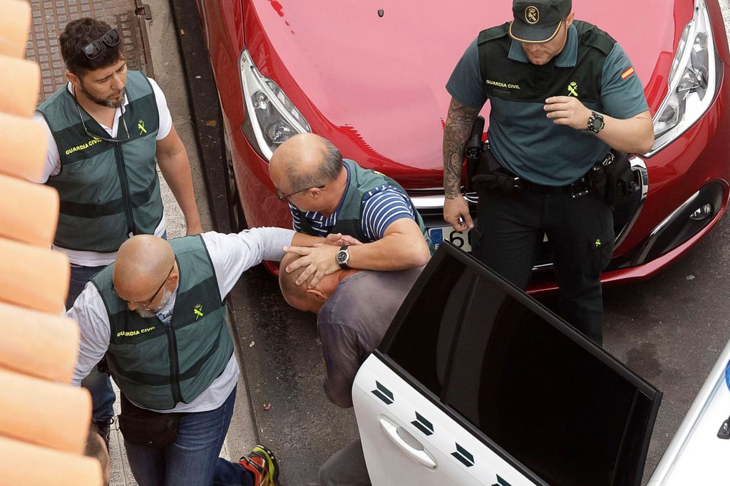 Polizeibeamte führen den Tatverdächtigen nach einer Hausdurchsuchung ab.