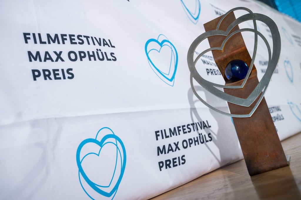 Ein Trophäe des Filmfestivals Max Ophüls Preis steht neben einem Banner mit dem Logo des Festivals.