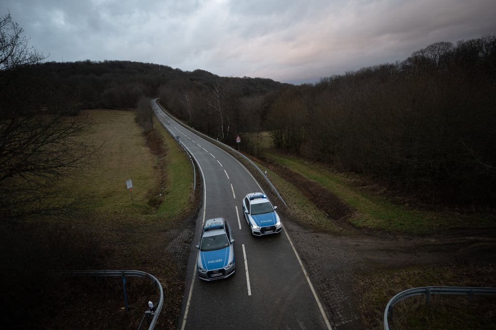 Zwei Polizeiwagen sperren die Kreisstraße 22 ab, auf der sich die Bluttat ereignet hat.