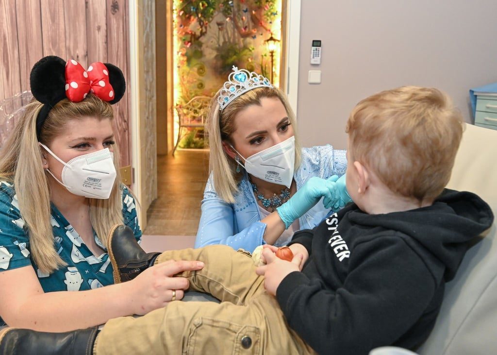 Kinderzahnärztin Anne Heinz (m.) verkleidet als Eiskönigin „Elsa“ und ihre Arzthelferin Ari Dema in der Kinderzahnarztpraxis „Dentiland“.