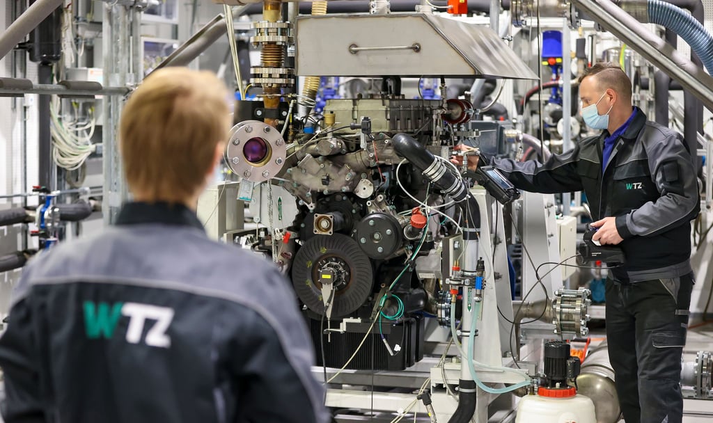 Arne Lazar (l), Doktorand und Projektleiter TRAINS-Projekt, und Nico Bernstein, Prüfstandstechniker, bereiten einen modifizierten Diesel-Nutzfahrzeugmotor vor.