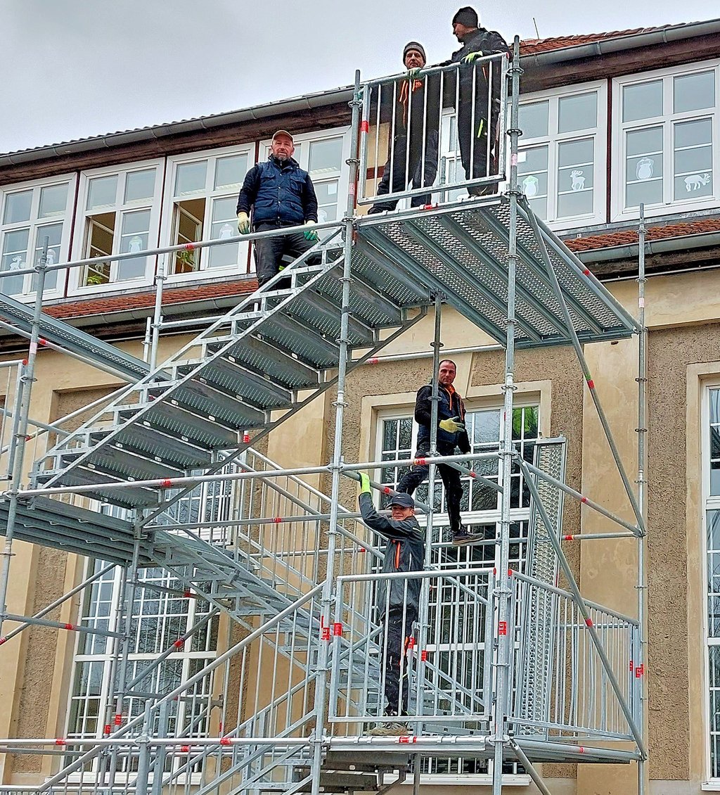 Mitarbeiter der Firma Böttcher Gerüstbau bauen an der Grundschule eine Metalltreppe auf.