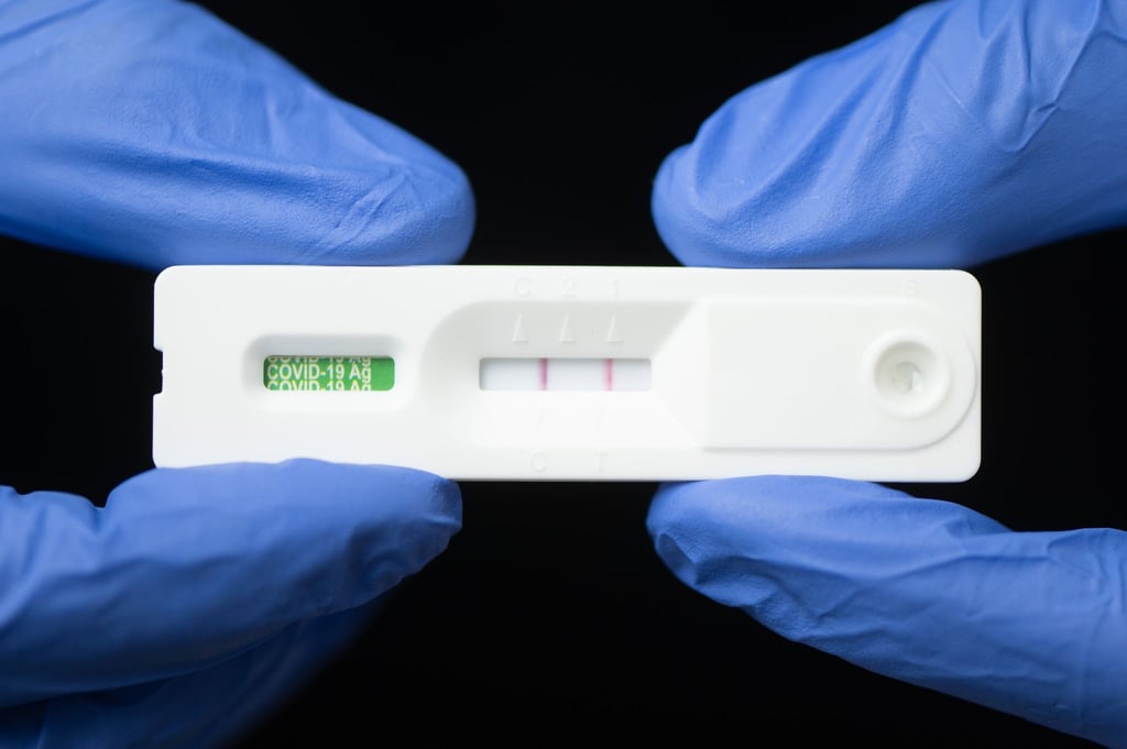 Eine Mitarbeiterin hält in einem Corona-Testcenter einen positiven Corona-Schnelltest.