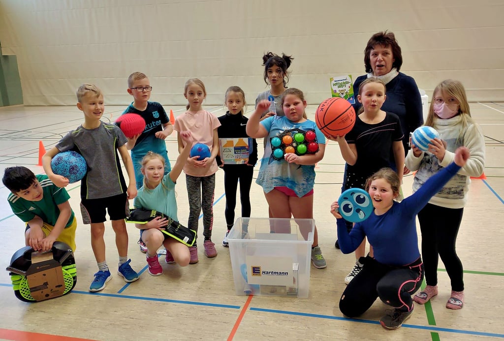Über eine von Edeka Hartmann gesponserte „AktioKit“-Sportmaterialkiste kann sich die Grundschule Havelberg freuen. Hier zeigen Kinder aus der Klasse 3b zusammen mit Edeka-Mitarbeiterin Karola Hinmüller, was sich so alles in der Kiste befindet.