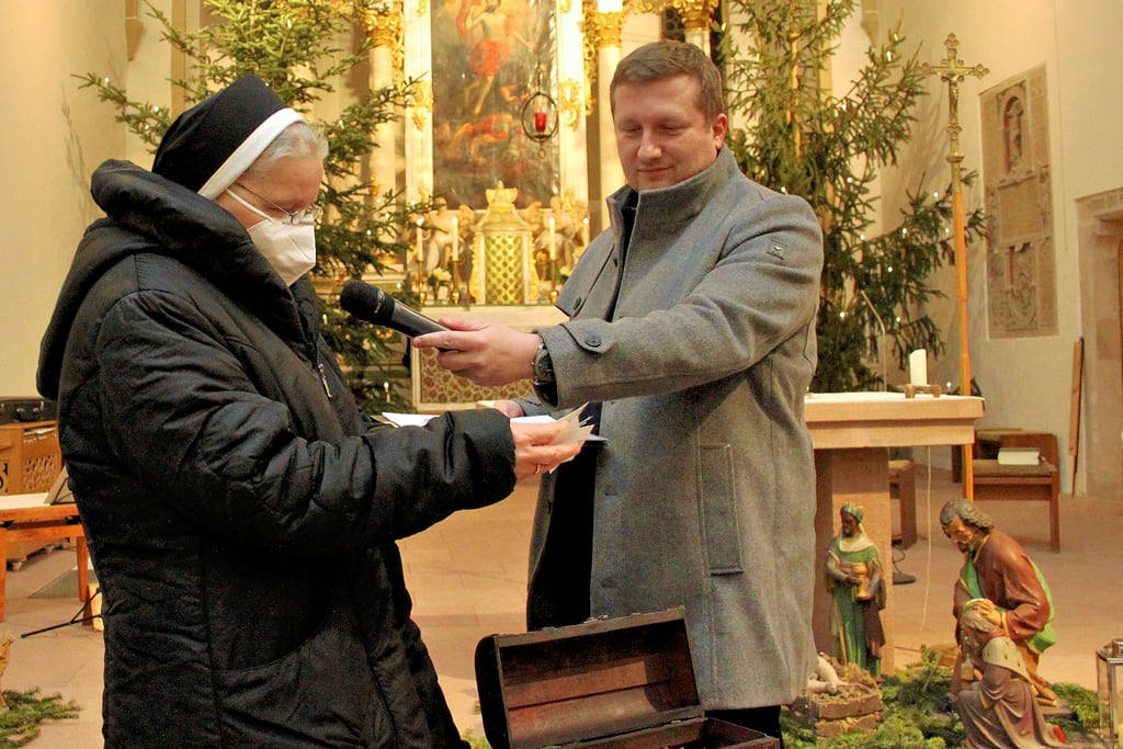 Ordensschwester Basilia zieht die Lose der Kirchenlotterie in Groß Ammensleben, Pfarrer Christian Kobert moderiert.