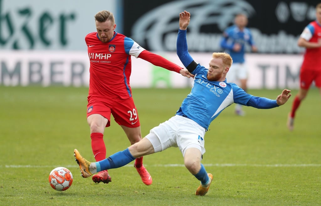 Nils Fröling (r) von Hansa Rostock im Kampf um den Ball mit Tobias Mohr (l) vom 1. FC Heidenheim.