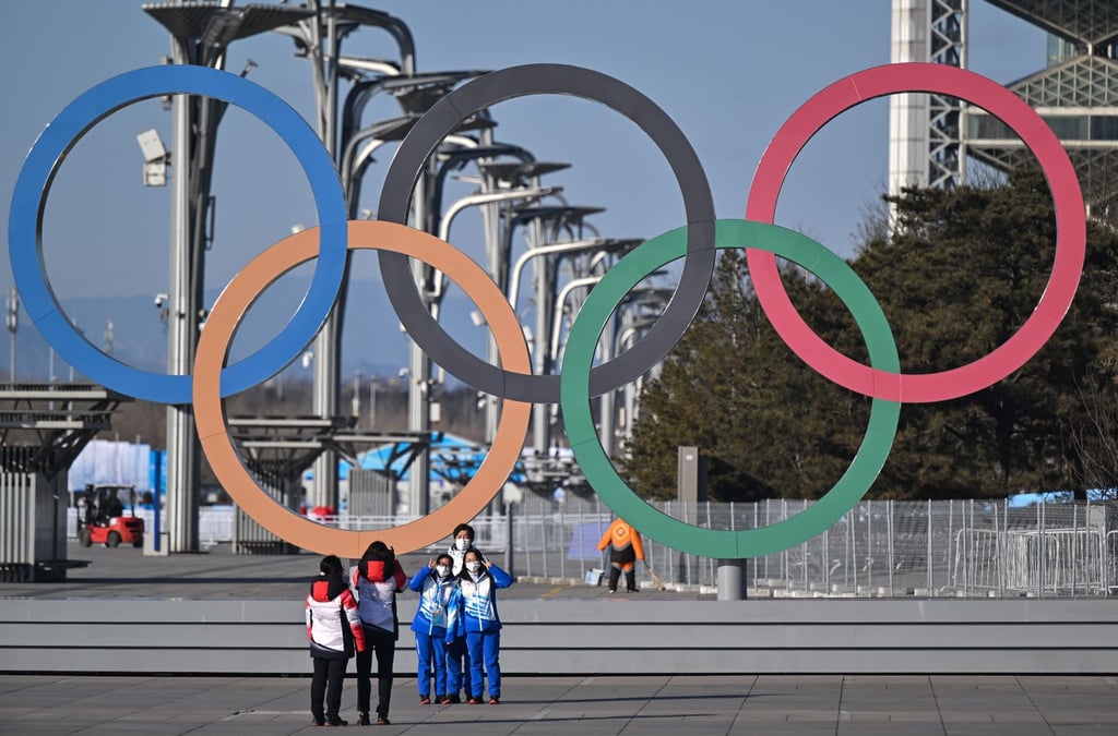 Von Olympia-Stimmung ist in Peking wenig zu spüren: Volunteers stehen vor den olympischen Ringen für ein Selfie.