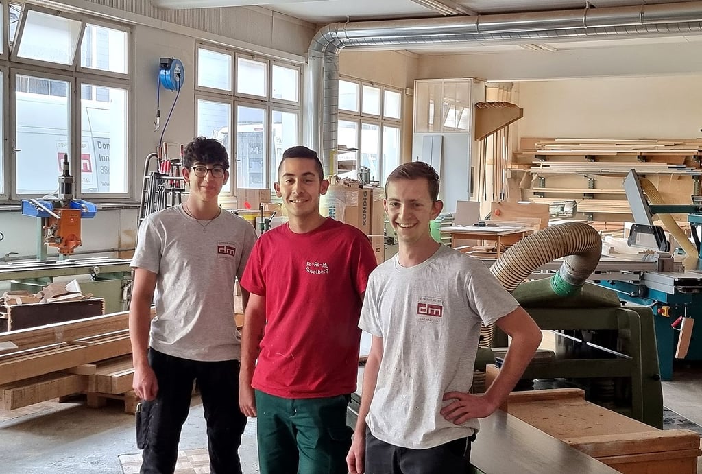 Im Schweizer Schreiner-Unternehmen in Schübelbach posieren die Auszubildenden Elia, Ricki und Merlin (von links) für ein gemeinsames Erinnerungsfoto.