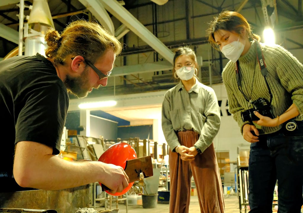 Glasmacher Torsten Rötzsch aus Coswig bei der Umsetzung eines Entwurfs der japanischen Austauschstudentin Izumi Yano (rechts), die den Arbeitsprozess konzentriert verfolgt und dokumentiert. Mit dabei auch die chinesische Studentin Yanshan Ou.