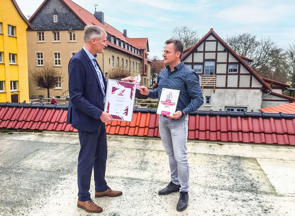 Über den Dächern von Nachterstedt nimmt Dennis Walter (r.) von Walter Dach und Bau die Auszeichnung „Top-Ausbilder“ von Burghard Grupe, Chef der Handwerkskammer Magdeburg, entgegen.