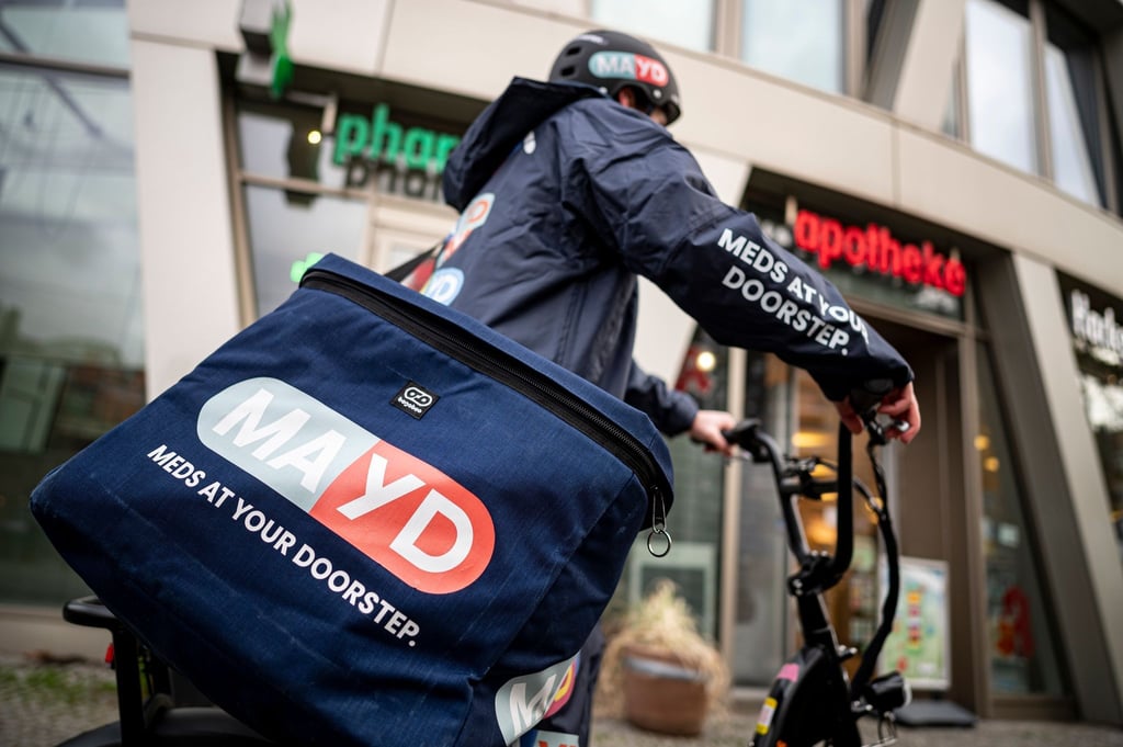 Ein Fahrer des Medikamenten-Lieferservice MAYD steht vor einer Apotheke. Per Mayd-App können Patienten rezeptfreie Medikamente bei ihrer Apotheke vor Ort bestellen.