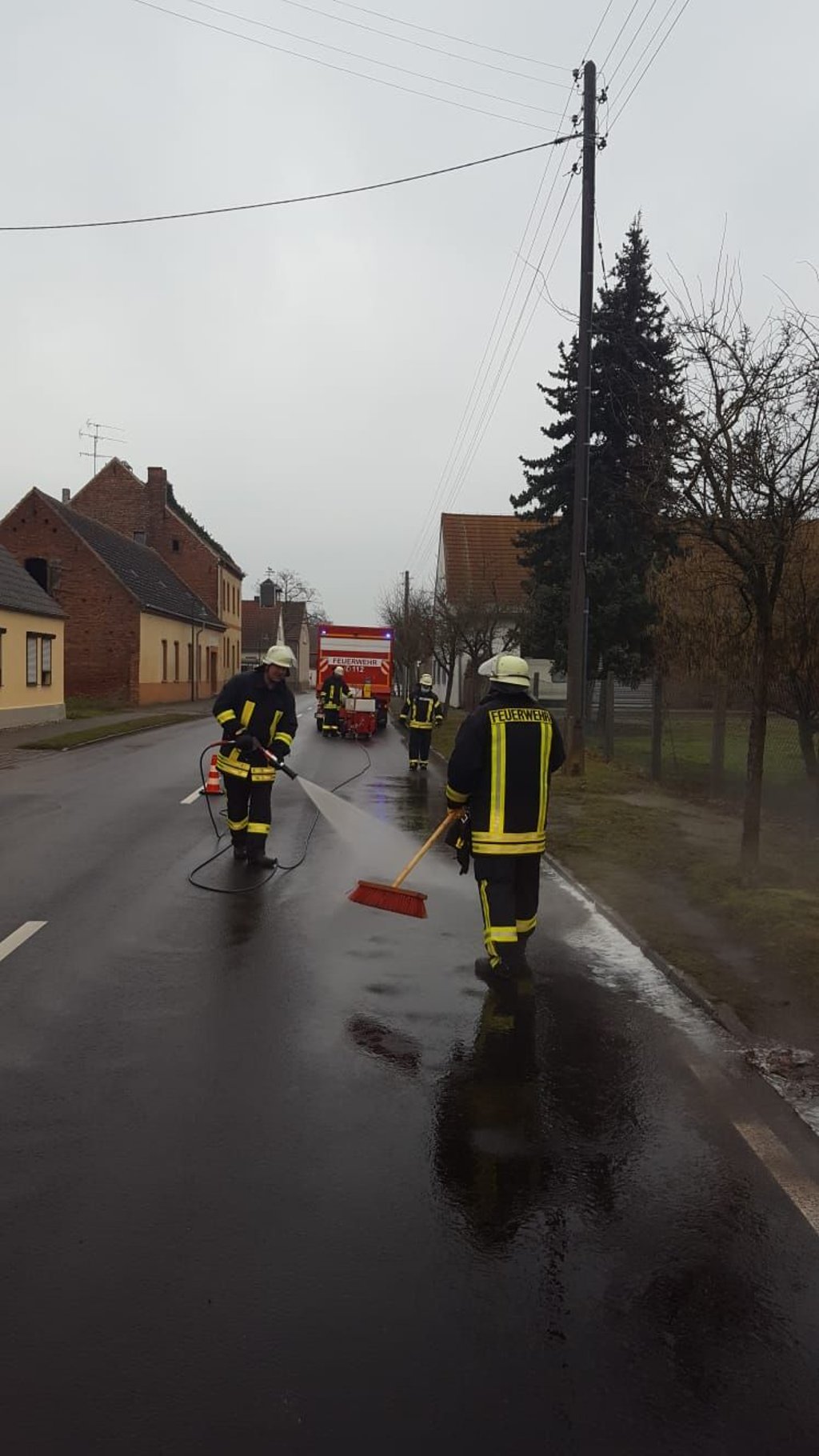 Kameraden der Feuerwehr Aken beseitigen die Dieselspur in Kühren.