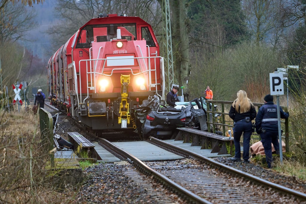 Polizisten stehen nach der Kollision eines Autos mit einem Zug an der Unfallstelle in Dierdorf. Ein Güterzug hatte das Auto an einem unbeschrankten Bahnübergang erfasst. Die Fahrerin des Wagesn starb.