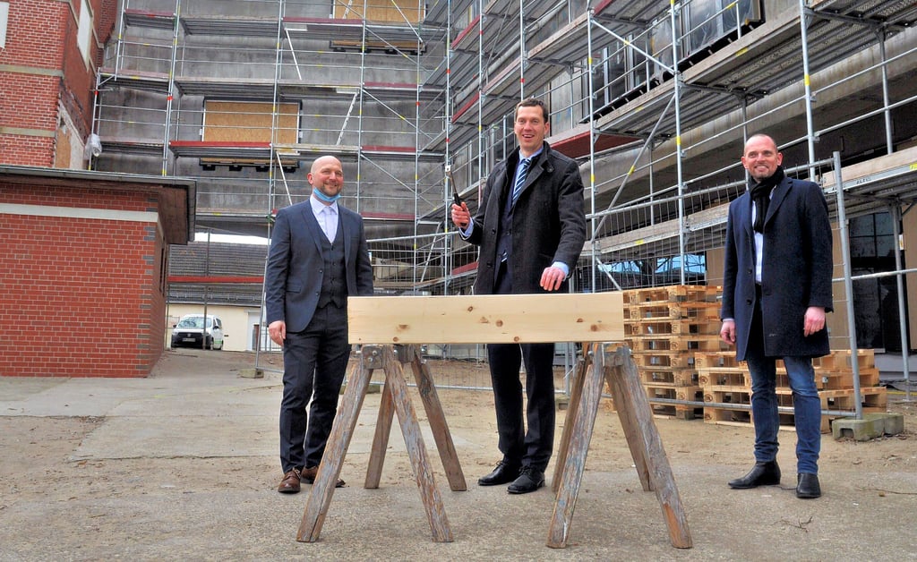 Landrat Steffen Burchhardt schlägt zum Richtfest symbolisch den letzten Nagel ein. Links Gymnasiumsleiter Volker Schütte, rechts der Architekt des Anbaus Dirk Becker.