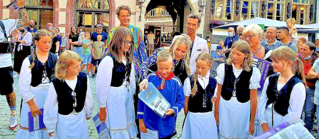 Jurorin Ilse DeLange gibt den Harzer Kramms eine Recall-Karte als Dankeschön für den spontanen Auftritt des Wernigeröder Mundartchores für die DSDS-Jury auf dem Marktplatz – nun warten die jungen Sänger sowie Chorleiterin Ines Friedrich (mit lilafarbenem Akkordeon und Brille) gespannt, wann sie im Fernsehen zu sehen sein werden.