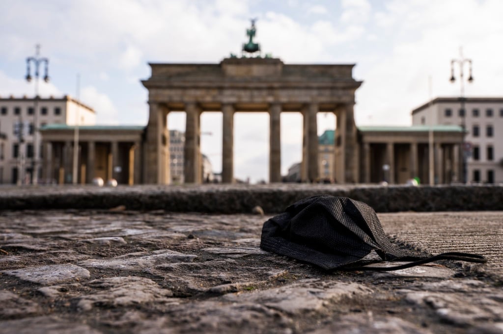 Eine schwarze Corona-Makse liegt auf dem Boden vor dem Brandenburger Tor.