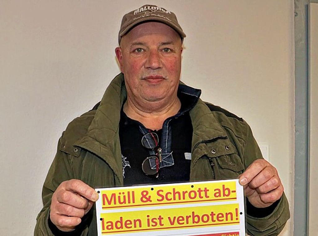 Uwe Michel zeigt ein Schild, dass Müllsünder von ihrem Tun abhalten soll.