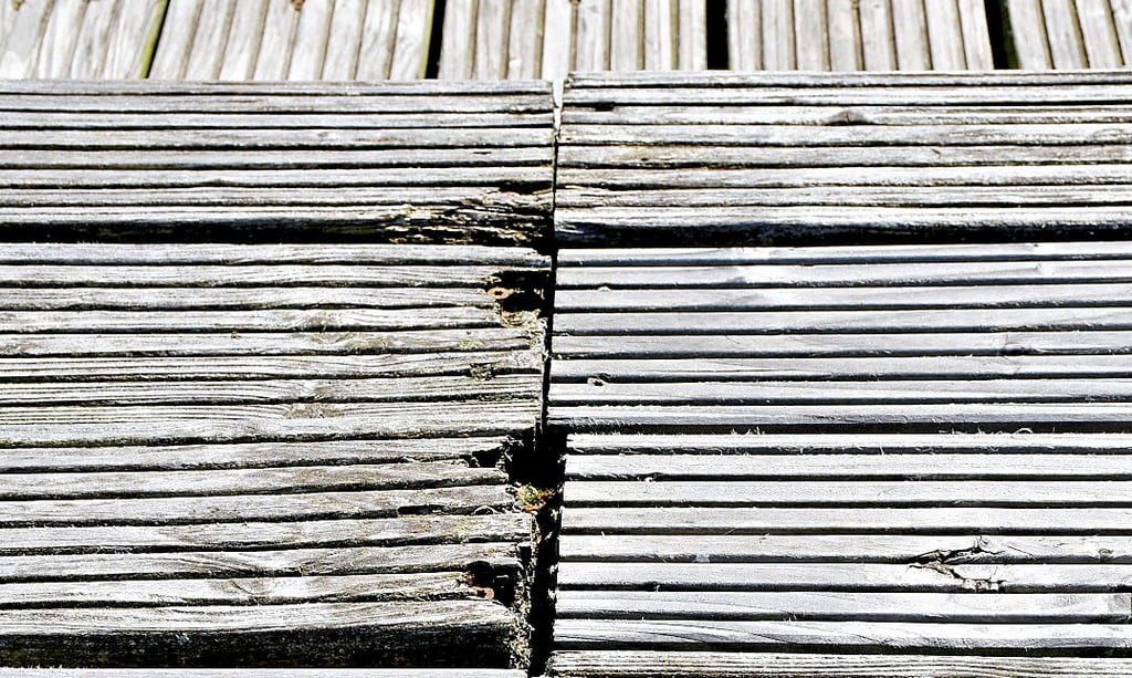 Ein Detailbild von einem Bereich der Sitzflächen: Holz ist sichtbar morsch und Schrauben fehlen.