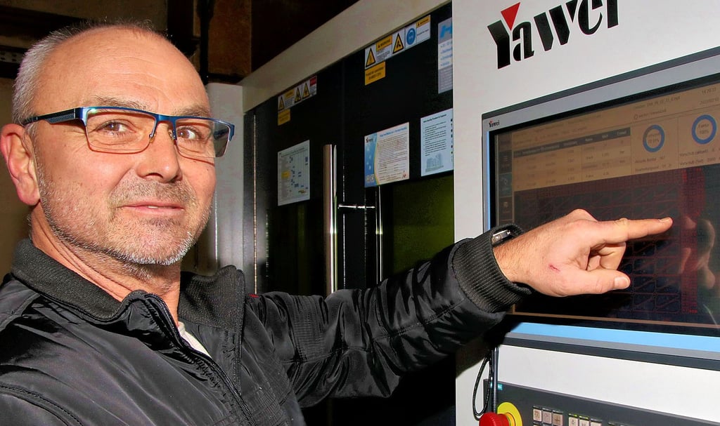 Dirk Ginsberg steht an dem neuen Faserlaser. Auf einem Monitor zeigt die Maschine den Fortschritt bei der Bearbeitung einer drei Meter langen Metallplatte an.