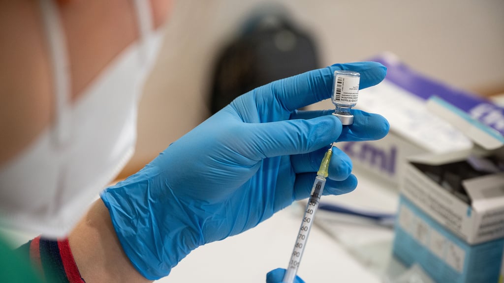 Eine Mitarbeiterin eines Impfteams zieht den Impfstoff von Biontech/Pfizer in eine Spritze auf.