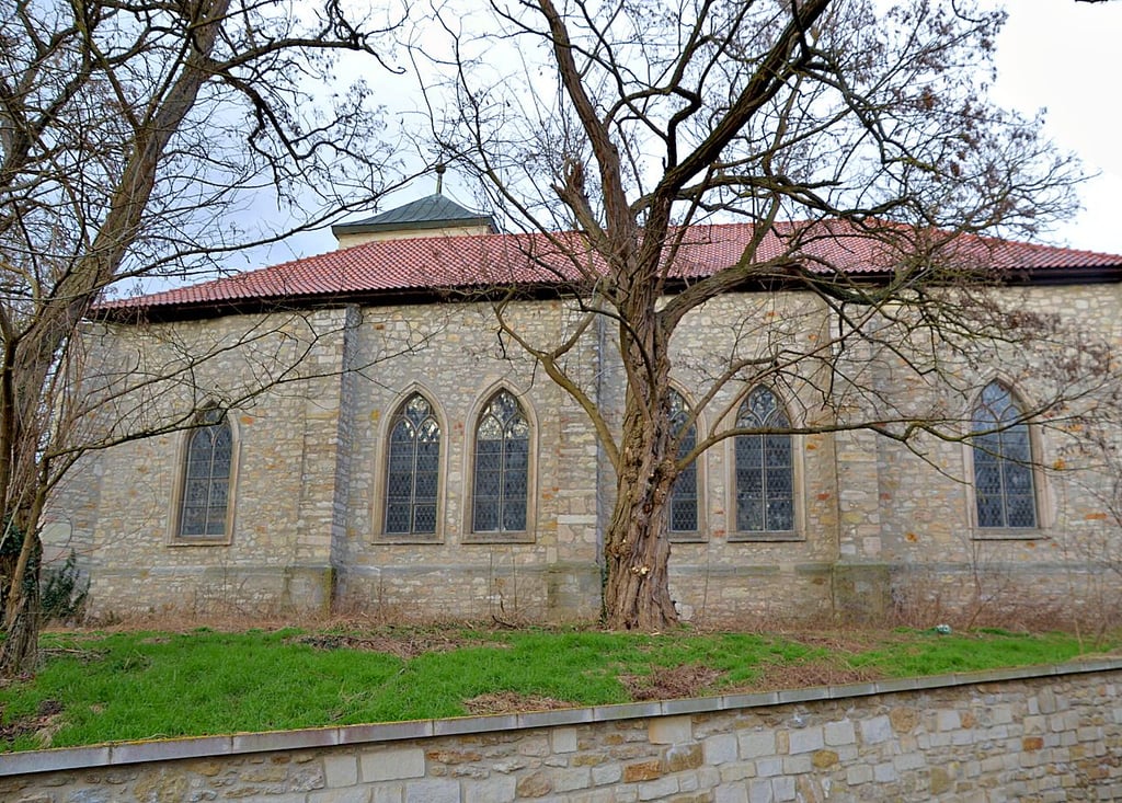 Die Kirche von der Sarre aus fotografiert. Der gekürzte Turm schaut kaum über das Dach des Schiffes hinaus.