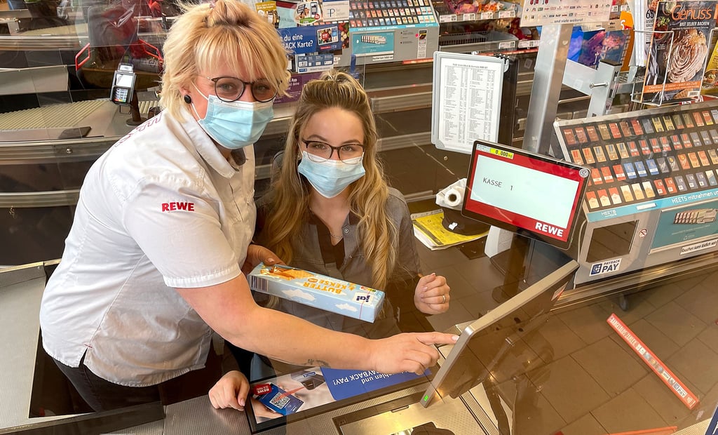 Hinter Plexiglas an der Supermarktkasse im Schönebecker Rewe an der Schillerstraße: Sonja Höldtke (l., die stellvertretende Marktleiterin) und Kassiererin Melanie Thienemann beim Einscannen von Produkten.