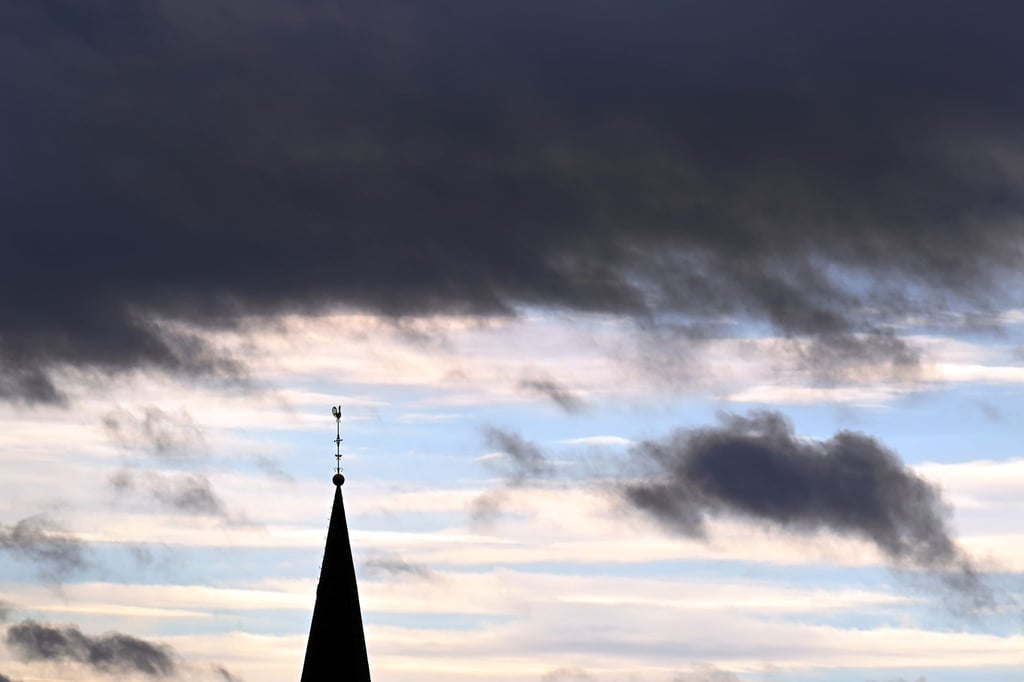 Hinter dem Turm der Pfarrkirche St.Cornelius ziehen Wolken.