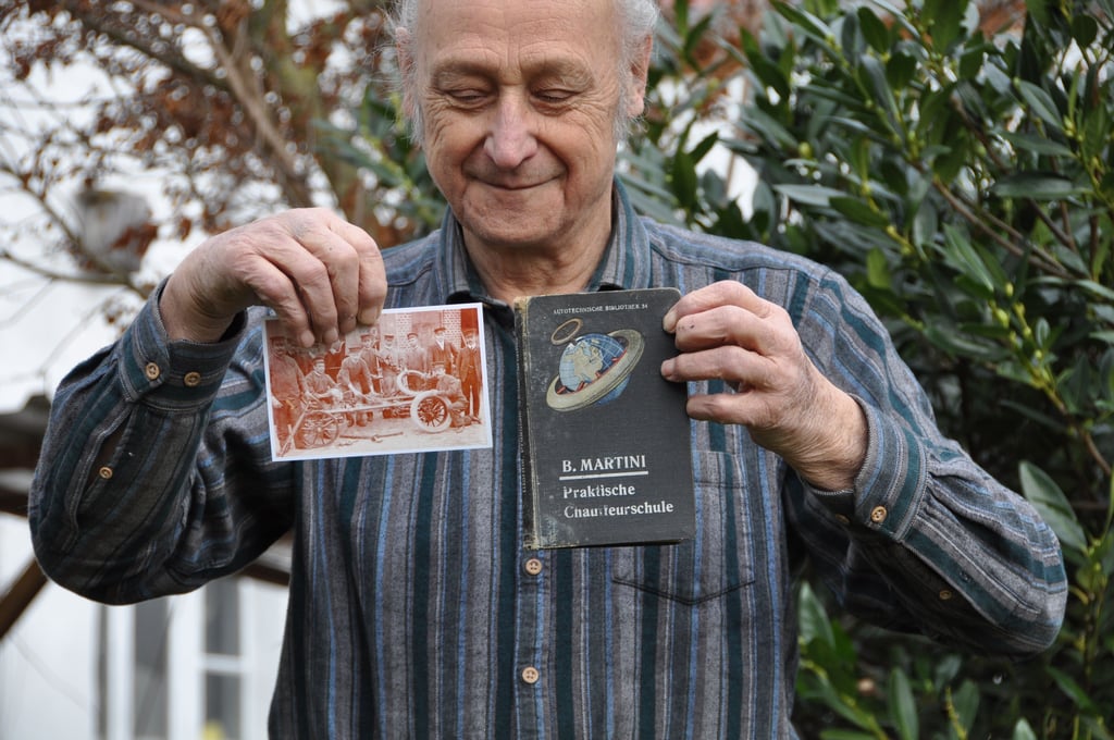 Joachim Zander mit einem Bild seines Opas vor der Chauffeurschule (direkt unter dem Zeigefinger) und dessen Lehrbuch.