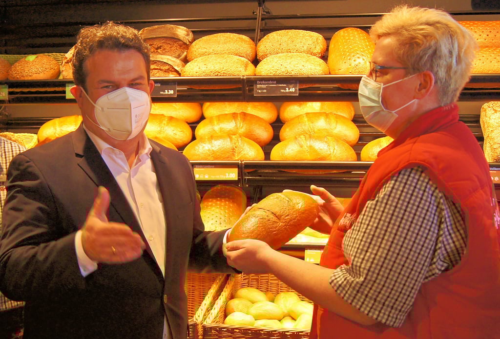 Bundesarbeitsminister Hubertus Heil kauft bei seinem Besuch in Wolmirstedt ein Brot bei Filialleiterin Bianka Müller-Kijas.