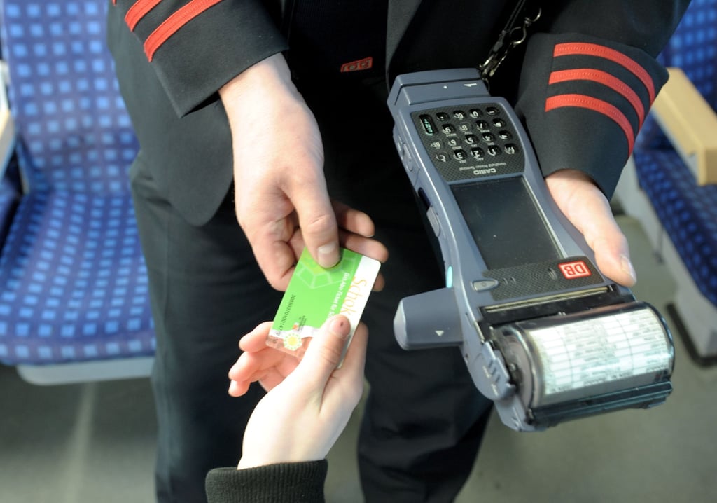 Ein Schaffner kontrolliert die Fahrkarte eines Bahnkunden.