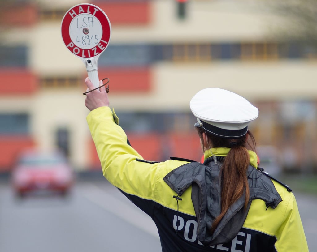 Verkehskontrolle: Eine Polizistin winkt mit einer Kelle ein Auto von der Straße.