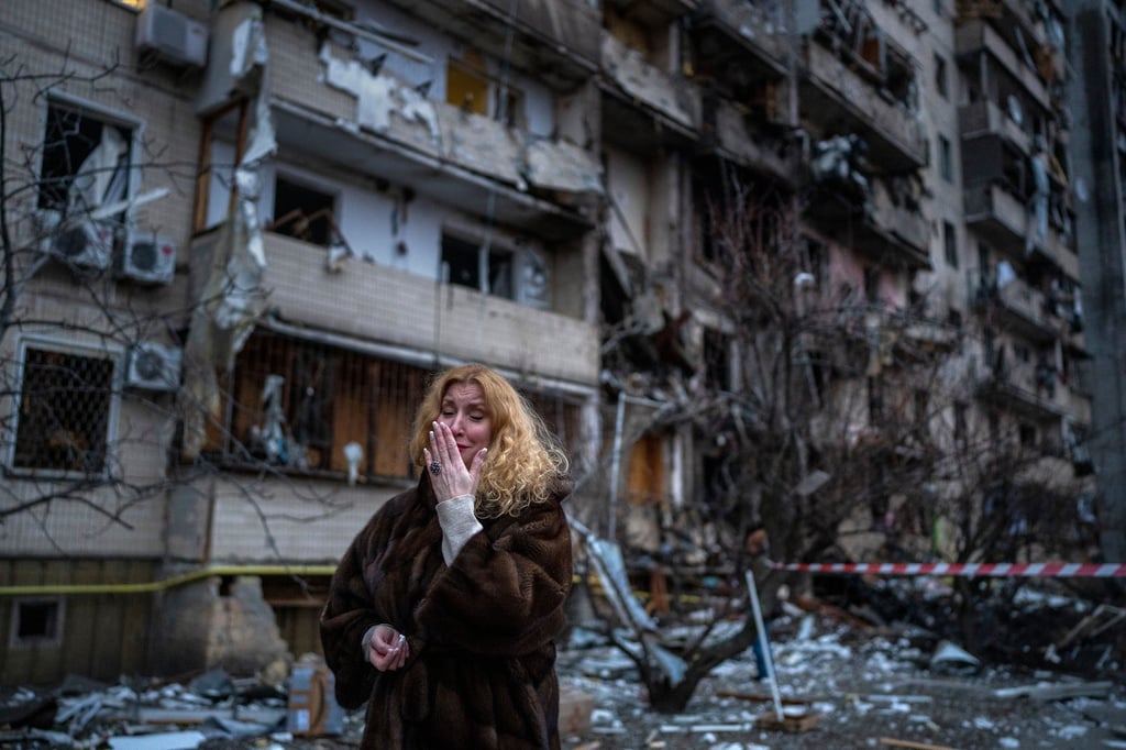 Eine Frau neben einem zerstörten Wohnhaus in der ukrainischen Hauptstadt Kiew. In der ukrainischen Hauptstadt gab es am Freitag heftige Gefechte und Raketeneinschläge.