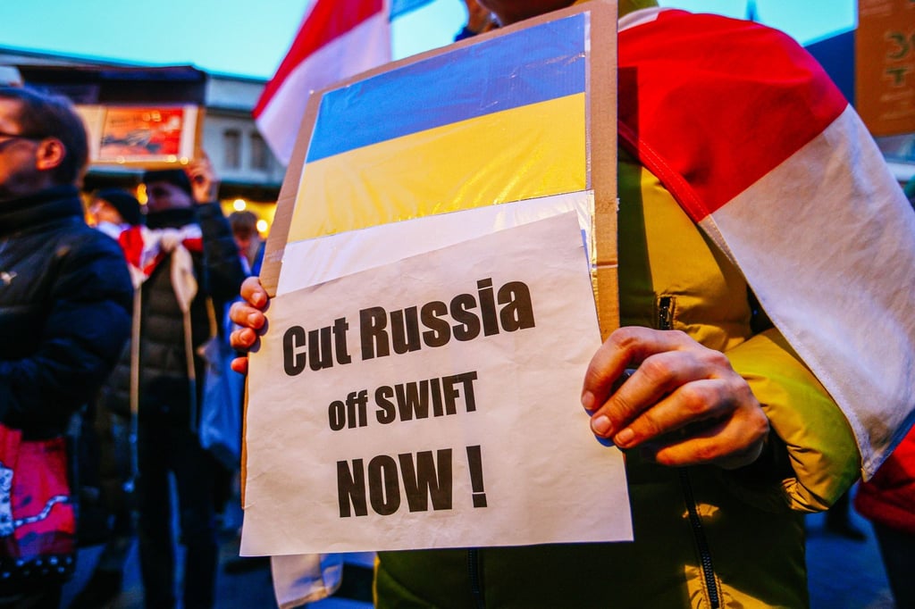 Ein Demonstrant hält ein Schild mit der ukrainischen Flagge und der Aufschrift „Russland jetzt abschneiden!“.