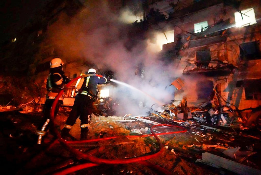 Feuerwehrleute löschen die Schäden an einem Gebäude nach einem Raketenangriff in Kiew.